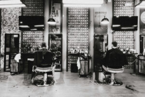 Barber styling client in bright studio with art and people interacting