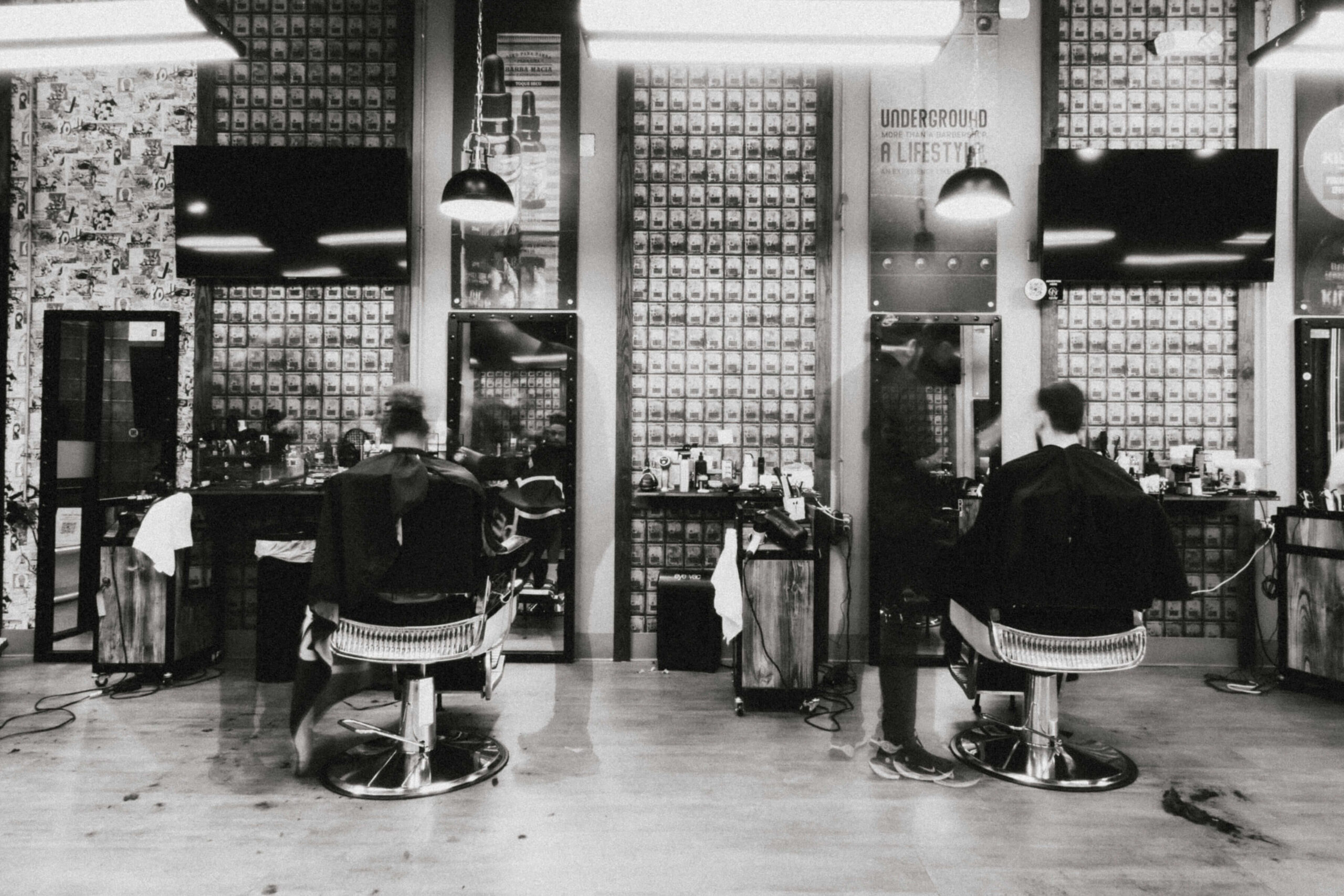 Barber styling client in bright studio with art and people interacting